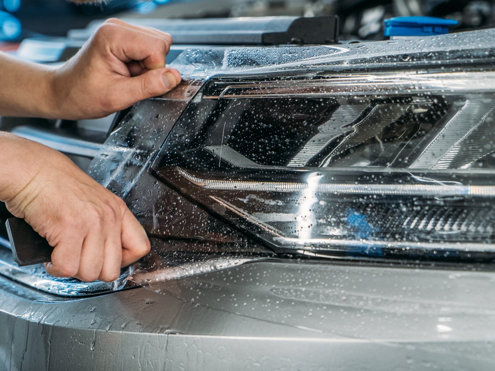 Technician applying clear PPF to a headlight and front bumper