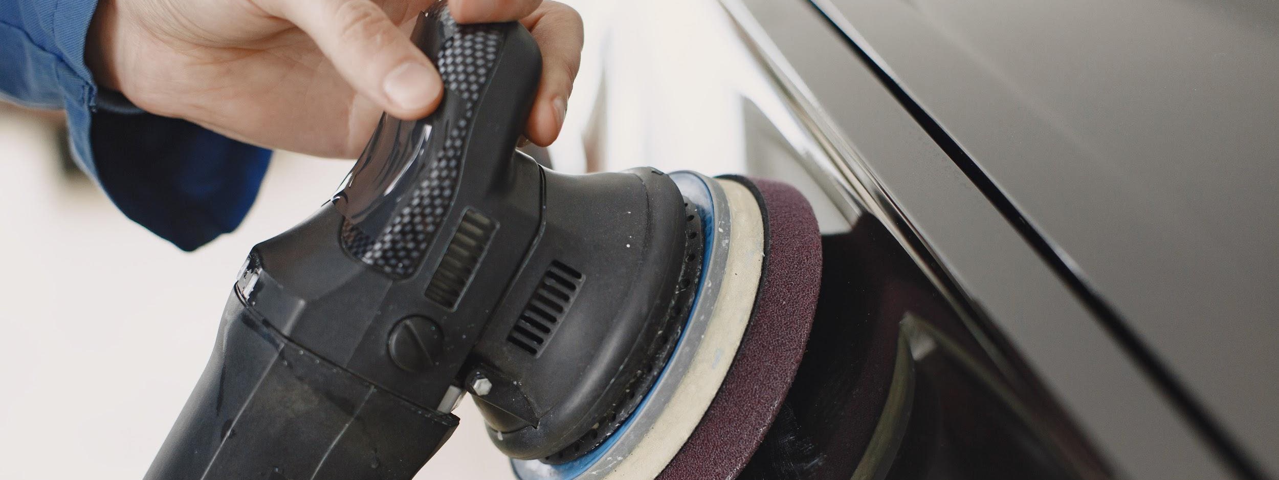 Technician machine-polishing a car