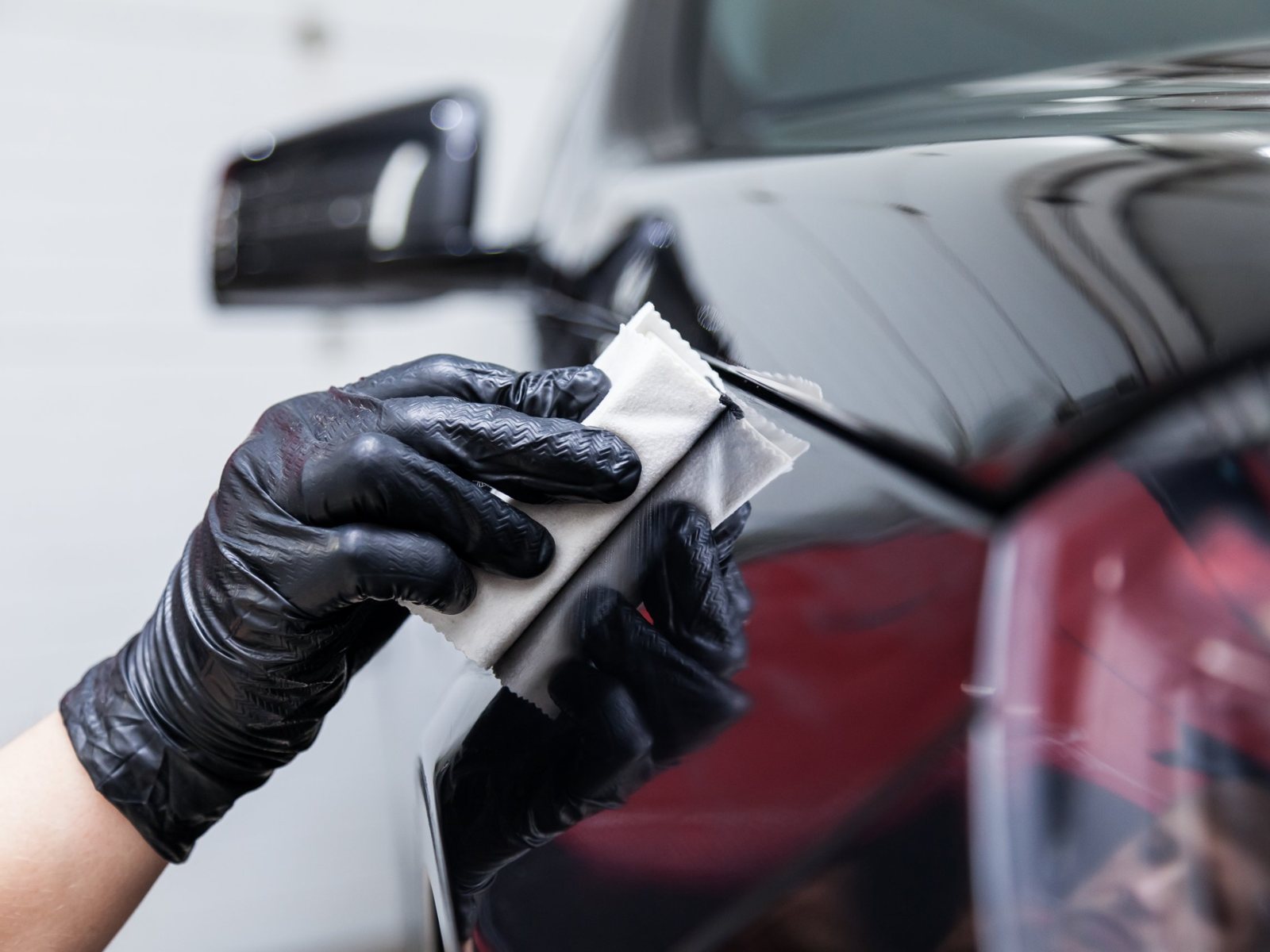 Technician applying coating to a black car