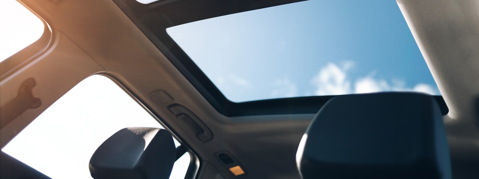 Looking up at a panoramic sunroof from inside the car
